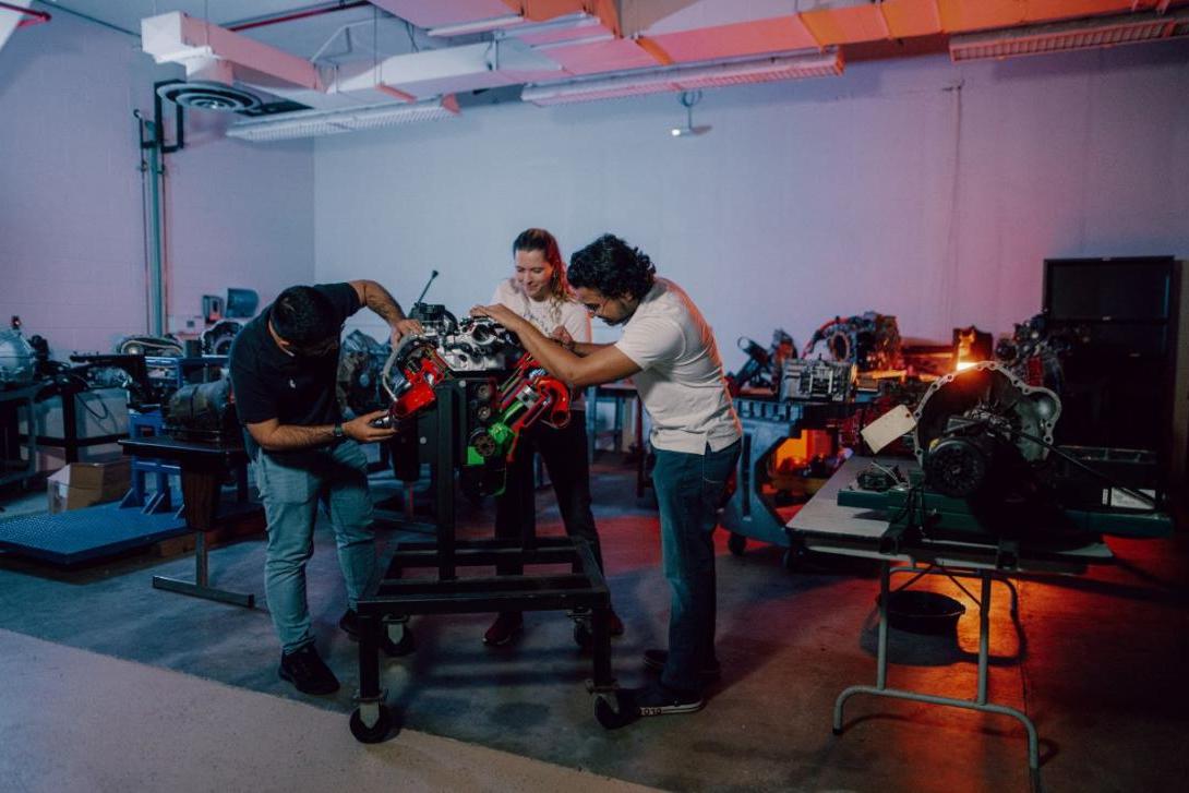 Three Kettering mechanical engineering students in the Car Lab take a close look at a car part