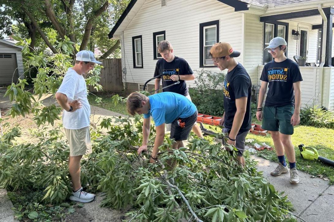 A group of five Kettering students cut and clear tree branches in a neighborhood for Service Saturday